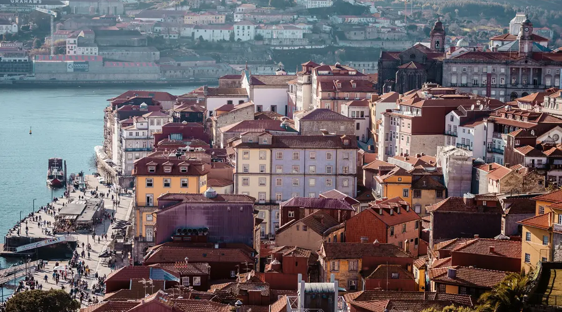 Aerial view of Porto's colorful houses along the Douro River, with red-tiled roofs and the Ribeira district in the background