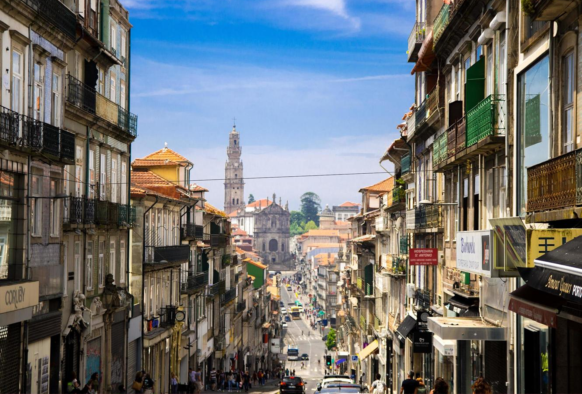 View of a street in Porto lined with traditional buildings on both sides, with the Clérigos Tower in the background
