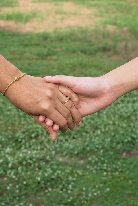 Two different hands holding each other, with grass in the background